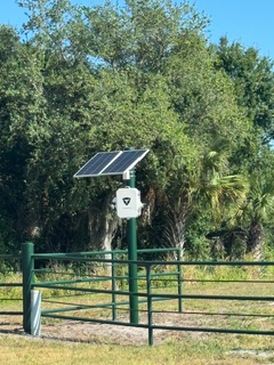 Front view of solar-powered surveillance camera installation mounted on a green pole